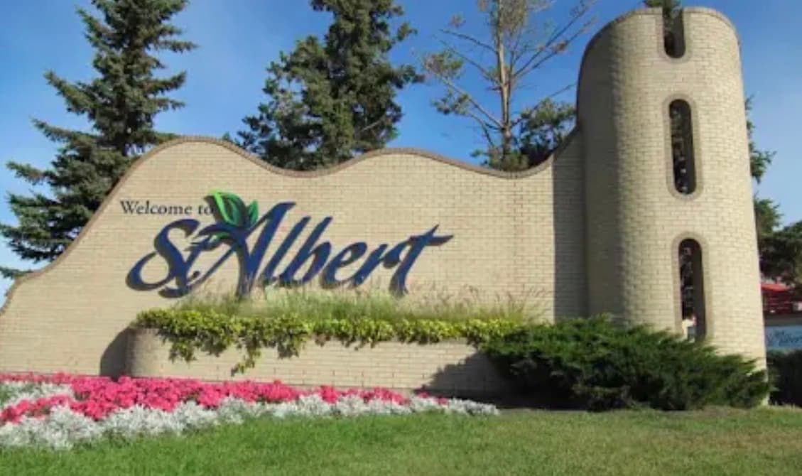 Welcome to St. Albert sign surrounded by summer flowers and trees